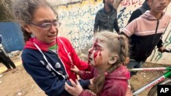 A wounded Palestinian girl is helped after an Israeli strike on Al Zawayda, central Gaza Strip, Dec. 28, 2023.