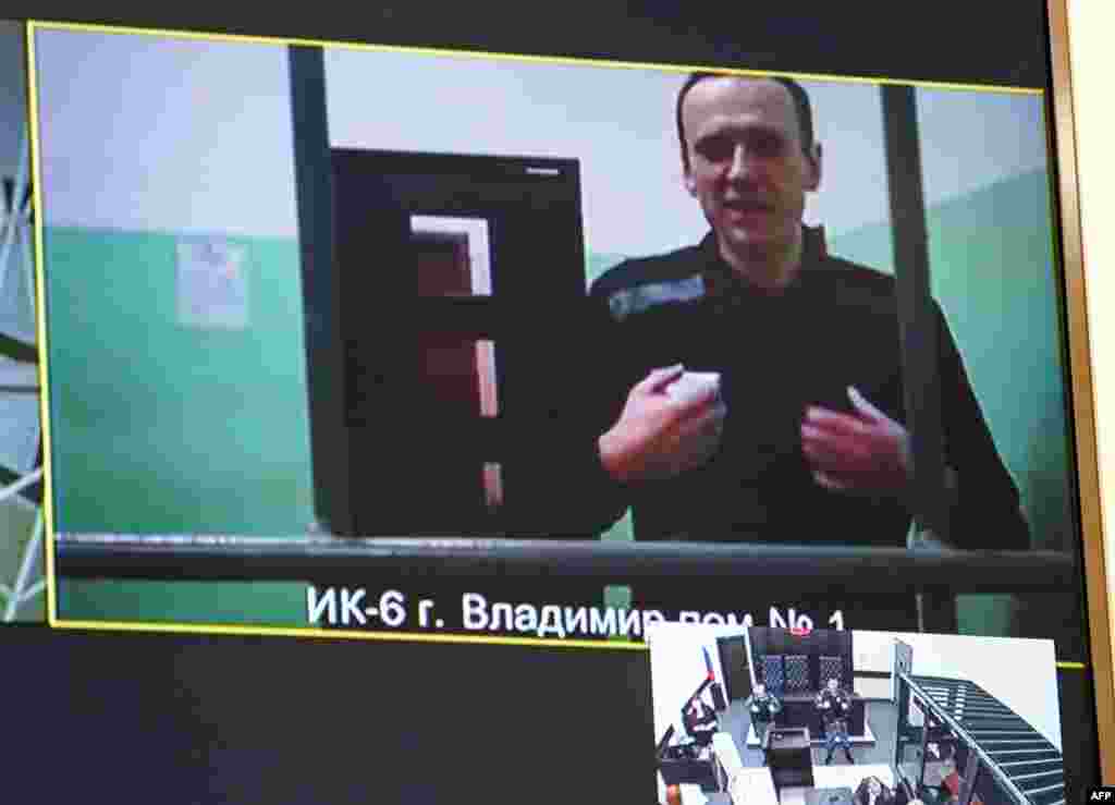 A screen shows jailed Kremlin critic Alexey Navalny as he arrives to listen to a hearing on an appeal lodged against a court decision to jail him for 19 years in a maximum security prison on extremism-linked charges, at a court in Moscow.