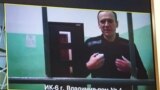 A screen shows jailed Kremlin critic Alexey Navalny as he arrives to listen to a hearing on an appeal lodged against a court decision to jail him for 19 years in a maximum security prison on extremism-linked charges, at a court in Moscow.