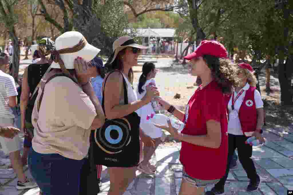 A Red Cross volunteer gives water to tourists at the foot of the Acropolis hill during a hot, windy day in Athens.&nbsp;Greece&#39;s Culture Ministry ordered the Acropolis closed for several hours in the middle of the day, while authorities warned of extreme heat conditions across much of the country.&nbsp;