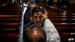 A priest makes the sign of the cross on the forehead of a man during the celebration of Ash Wednesday in Bogota, Colombia.