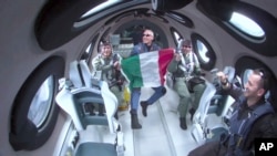 This June 29, 2023, image provided by Virgin Galactic shows Italian Air Force Colonel Walter Villadei holding an Italian flag as he and other Italian researchers experience weightlessness aboard Virgin Galactic's rocket-powered spaceplane. 