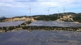 FILE - Solar panels work near wind turbines in Quy Non, Vietnam on June 11, 2023. 