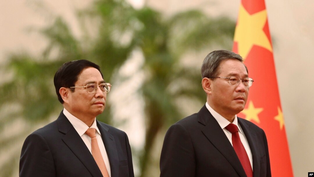 Vietnam's Prime Minister Pham Minh Chinh, left, and Chinese Premier Li Qiang listen to national anthems during a welcome ceremony in the Great Hall of the People in Beijing, June 26, 2023. (Pool photo via AP)