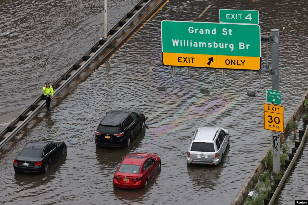 Un oficial de la policía ayuda a los automovilistas atrapados en una calle inundada después de las fuertes lluvias mientras los restos de la tormenta tropical Ofelia provocan inundaciones en todo el Atlántico medio y el noreste, en FDR Drive en Manhattan, cerca del puente Williamsburg, en la ciudad de Nueva York.