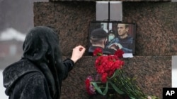 FILE — A woman touches a photo of Alexey Navalny at the Memorial to Victims of Political Repression in St. Petersburg, Russia, Feb. 17, 2024. At least four journalists were detained in Russia last week while reporting on gatherings to mourn Navalny's death, according to reports. 