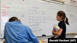 FILE - Noelle Trotter, right, walks past French lessons written on the board at the International School of Louisiana in New Orleans, Nov. 11, 2011.