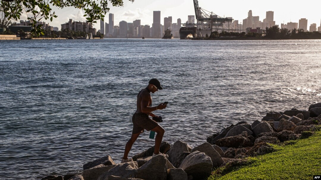 Seorang pria tampak berjalan di atas bebatuan di South Point Park di Miami Beach, Florida, di tengah gelombang panas yang melanda wilayah AS, pada 26 Juni 2023. (Foto: AFP/Giorgio Viera)