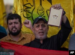 Seorang Irak mengangkat salinan Al-Qur'an saat protes di Tahrir Square, 20 Juli 2023 di Baghdad, Irak. (Foto: AP)