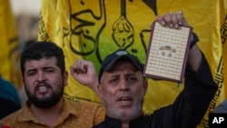 An Iraqi raises a copy of the Quran, Muslims' holy book, during a protest in Tahrir Square, July 20, 2023 in Baghdad, Iraq.