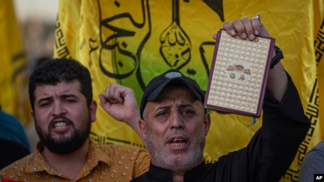 An Iraqi raises a copy of the Quran, Muslims' holy book, during a protest in Tahrir Square, July 20, 2023 in Baghdad, Iraq.