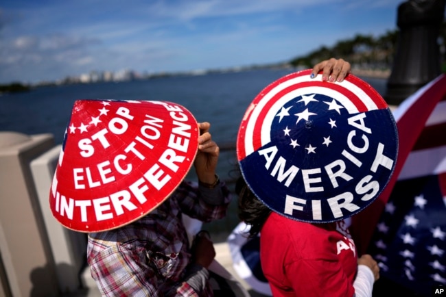 Members of a California group called Patriots for Freedom, who were in town to attend a fundraiser for Republican presidential candidate Donald Trump, wear hats showing their support outside his Mar-a-Lago estate, Feb. 16, 2024, in Palm Beach, Fla.