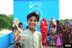 تھر کے پانی پراجیکٹ سے صاف پانی حاصل کرتے ہوئے ایک مسکراتے بچے کی تصویر