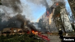 A firefighter looks at an apartment building and cars that burn after a Russian air strike, amid Russia's attack on Ukraine, in Kharkiv, Ukraine, Aug. 30, 2024.