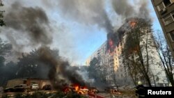 A firefighter looks at an apartment building and cars that burn after a Russian air strike, amid Russia's attack on Ukraine, in Kharkiv, Ukraine, Aug. 30, 2024.
