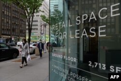 Para pejalan kaki berjalan melewati gedung perkantoran di pusat kota Manhattan, New York City, 7 Mei 2021. (Angela Weiss / AFP)