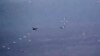 In this image from video released by the U.S. Air Force, Russian military SU-34 and SU-35 aircraft release flares in the flight path of a U.S. Air Force MQ-9 Reaper drone, lower left, July 6, 2023, over Syria. 