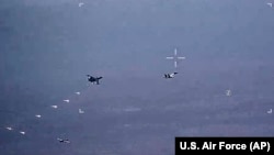 In this image from video released by the U.S. Air Force, Russian military SU-34 and SU-35 aircraft release flares in the flight path of a U.S. Air Force MQ-9 Reaper drone, lower left, July 6, 2023, over Syria. 