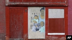 FILE - Artwork covers a boarded-up door outside a blighted building in Baltimore, April 4, 2013. A November 2024 ballot initiative proposes giving new parents in Baltimore a $1,000 “baby bonus” to help reduce childhood poverty.