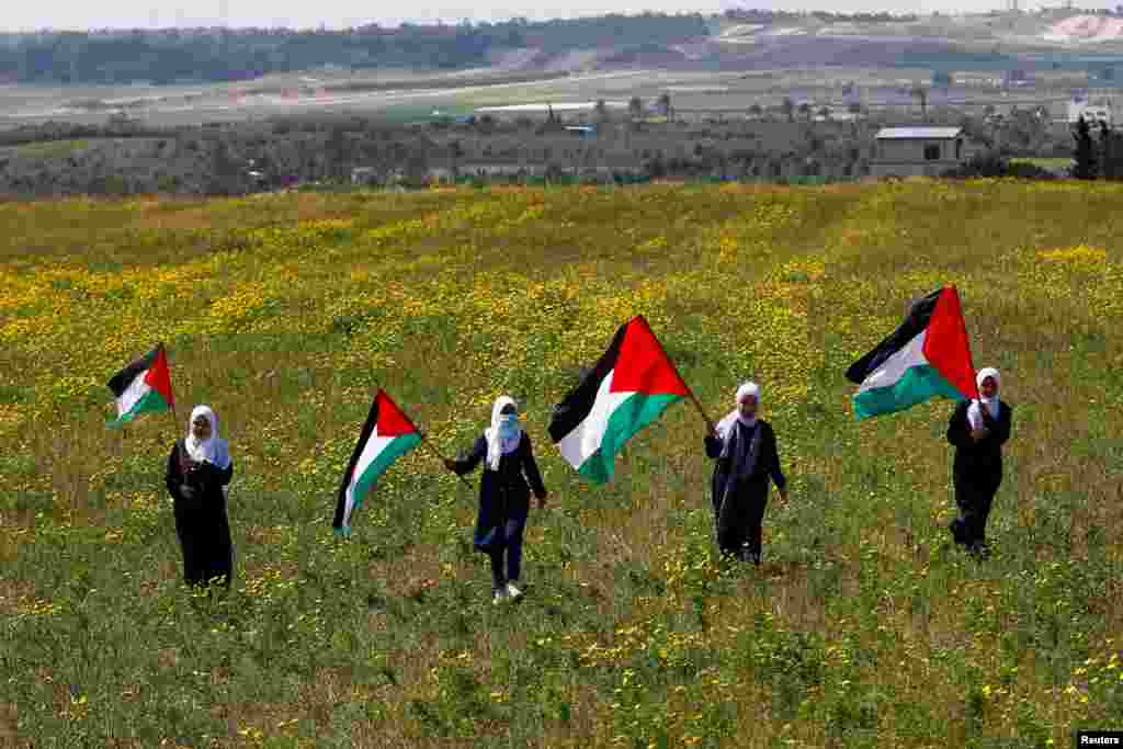 Palestinians hold flags as they mark "Land Day," an annual commemoration of six Arab citizens of Israel who were killed by Israeli security forces during demonstrations over land confiscations in 1976, in the southeast of Gaza City.
