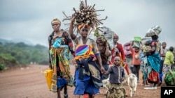 FILE - Residents flee fighting between M23 rebels and Congolese forces near Kibumba, some 20 kilometers north of Goma, Democratic Republic of Congo, on Oct. 29, 2022. 