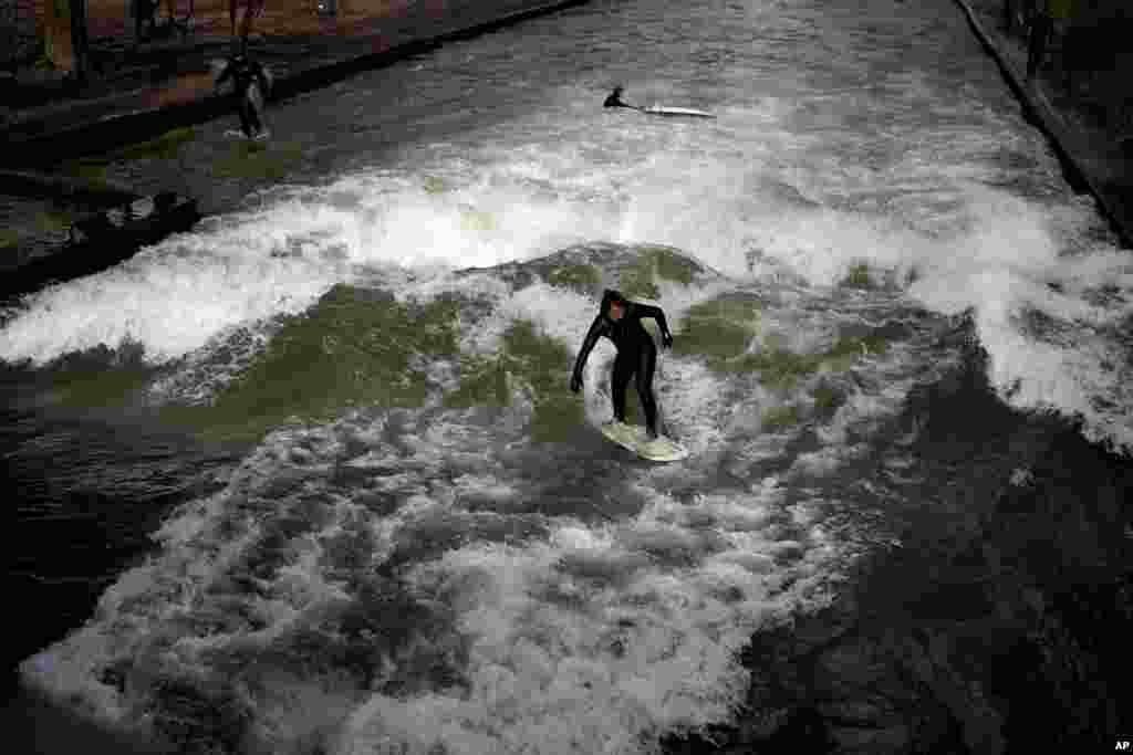 A surfer rides on an artificial wave in the river &#39;Eisbach&#39; at the &#39;Englischer Garten&#39; (English Garden) downtown in Munich, Germany.