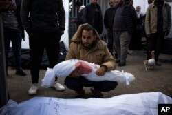 A man holds the body of his daughter who was killed in the Israeli bombardment of the Gaza Strip, at a hospital morgue in Rafah, Feb. 21, 2024.
