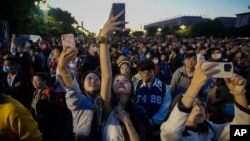 FILE - People take smartphone photos of the crowd on a street near Tiananmen Square as visitors gather to watch a flag-raising ceremony on the National Day in Beijing, Sunday, Oct. 1, 2023. (AP Photo/Andy Wong, File)