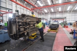A worker at the vehicle dismantler company Charles Trent Ltd unbolts an engine from an old vehicle for reuse or recycling, on a disassembly line in Poole, Britain, June 7, 2023.