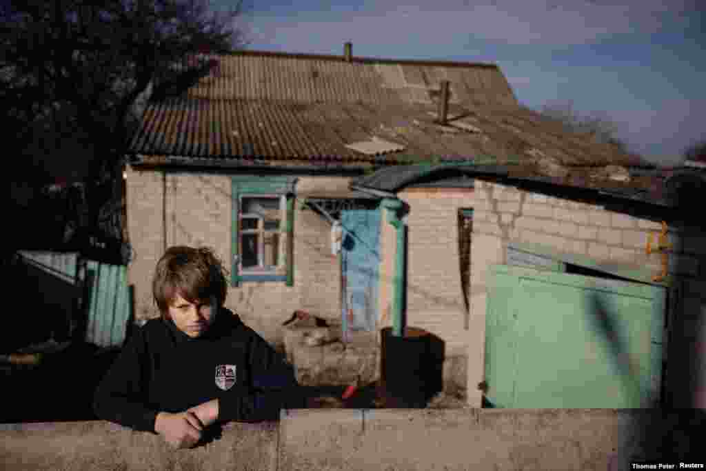 Mykyta, un niño de 13 años con problemas de aprendizaje, aguarda en la entrada de su casa. Vive en el pueblo de Tetyanivka, a menos de 30 kilómetros de la guerra que azota la región ucraniana de Donetsk.