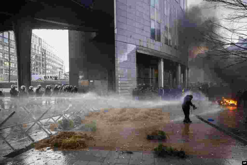 Anti-riot police use water to break up a protest by farmers outside the European Parliament, as European leaders meet for an EU summit in Brussels, Belgium. (AP Photo/Thomas Padilla)