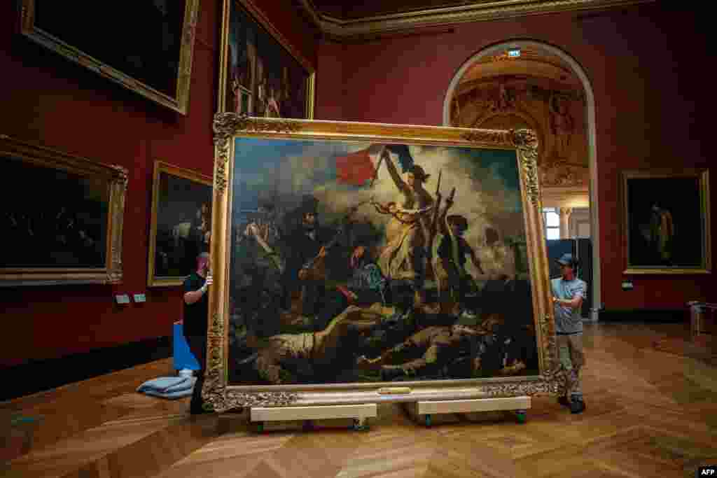 Gallery workers remove the painting &quot;Liberty Leading the People&quot; by Delacroix (1798-1863) from its picture rails at the Louvre Museum in Paris, France.