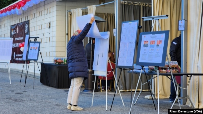 Seorang pemilih memeriksa informasi daftar pemilih tetap di depan TPSLN Los Angeles, Sabtu, 10 Februari 2024. (Foto: Rivan Dwiastono/VOA)
