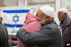 Israeli released hostage Bilal Al-Ziyadne, left, reunites with his family at Soroka Medical Center in Be’er Sheva, Israel, on Dec. 1, 2023. (GPO via AP)