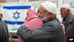 This handout photo provided by GPO on Dec. 1, 2023, shows Israeli released hostage Bilal Al-Ziyadne, left, reuniting with his family at Soroka Medical Center in Be’er Sheva, Israel.