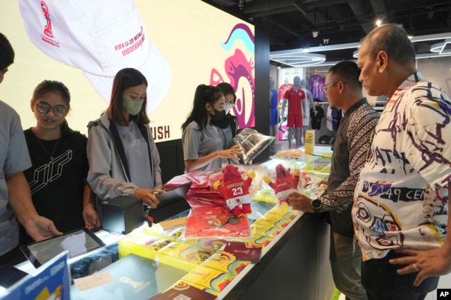 Petugas toko melayani pelanggan yang berbelanja merchandise resmi FIFA U-20 World Cup di sebuah pusat perbelanjaan di Jakarta, Jumat, 31 Maret 2023. (Foto: AP)