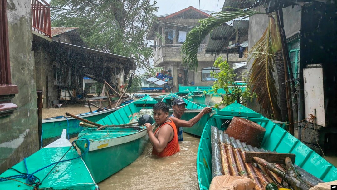 Warga membawa perahu mereka untuk mencegah hanyut oleh sungai yang meluap akibat Topan Doksuri di kota Laoag, provinsi Ilocos Norte, Filipina utara, 26 Juli 2023. (AP Photo/Bernie Sipin Dela Cruz)