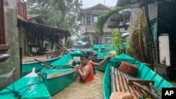 Warga membawa perahu mereka untuk mencegah hanyut oleh sungai yang meluap akibat Topan Doksuri di kota Laoag, provinsi Ilocos Norte, Filipina utara, 26 Juli 2023. (AP Photo/Bernie Sipin Dela Cruz)