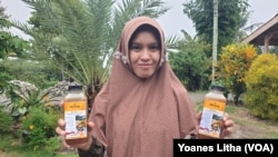 Karisma (29) memperlihatkan kemasan botol berisi madu yang dihasilkan dari kegiatan budi daya lebah madu Trigona di dusun Tamanjeka, desa Masani, Kabupaten Poso, Sulawesi Tengah, Minggu, 14 Januari 2024. (Foto: VOA/Yoanes Litha)