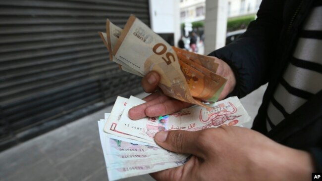 A man holds Algerian and European, top, bank notes Feb. 9, 2024, in Algiers, Algeria.