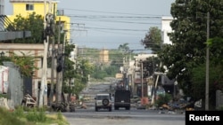 A Haitian National Police car and an armored vehicle drive through a desolated street in the Champ de Mars neighborhood, in Port-au-Prince, Haiti, June 27, 2024. The Biden administration is offering deportation relief to Haitians in the U.S., because of security issues in Haiti.