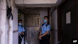 Polisi berdiri di luar sebuah apartemen di mana tiga anak dibunuh di Sham Shui Po, Hong Kong, Senin, 5 Juni 2023. (AP/Louise Delmotte)