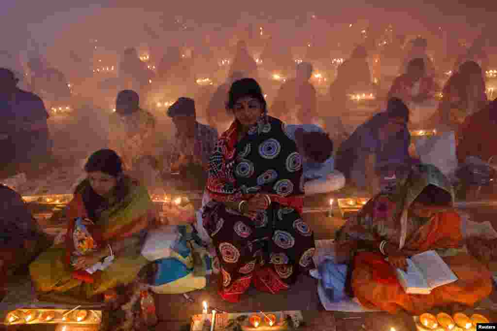 Hindu devotees sit together on the floor of a temple with oil lamps, praying to Lokenath Brahmachari, a Hindu saint, as they observe Rakher Upabash, in Narayanganj, Bangladesh.