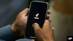 FILE - A man opens social media app TikTok on his cell phone, in Islamabad, Pakistan, July 21, 2020.