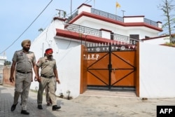 FILE - Punjab police personnel walk past near the residence of 'Waris Punjab De' chief Amritpal Singh, in village Jallupur Khera about 45 km from Amritsar on March 19, 2023.
