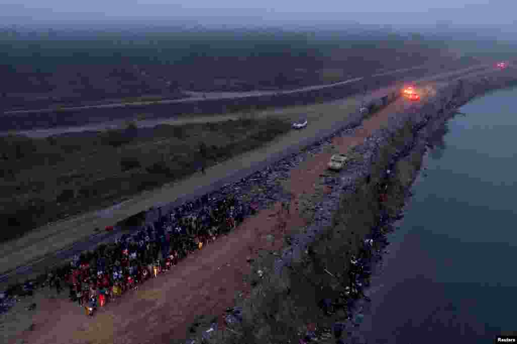 Rombongan migran, yang kebanyakan berasal dari Venezuela dan Honduras, ditahan di pinggiran sungai Rio Grande River setelah berhasil menyeberangi sungai tersebut untuk menuju Eagle Pass, Texas, pada 23 Desember 2023. (Foto: Reuters/Cheney Orr)