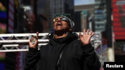 A person looks up to view a partial solar eclipse, where the moon will partially blot out the sun, at Times Square in New York City, April 8, 2024.