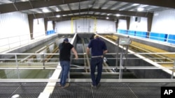 FILE - Dave Hoffman, left, and Paul Ziemkiewicz of West Virginia University's Water Research Institute check on clarifying pools at a facility they run where rare earth minerals are separated from acidic groundwater, June 25, 2024, in Mount Storm, W.Va.