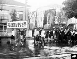 1947년 7월 23일 북한 평양에서 열린 미소공동위원회 환영 퍼레이드에서 북조선로동당중앙본부 참가자들이 스탈린과 김일성의 대형 초상화를 들고 있다,