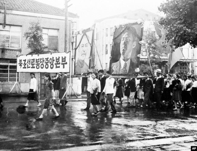 1947년 7월 23일 북한 평양에서 열린 미소공동위원회 환영 퍼레이드에서 북조선로동당중앙본부 참가자들이 스탈린과 김일성의 대형 초상화를 들고 있다,